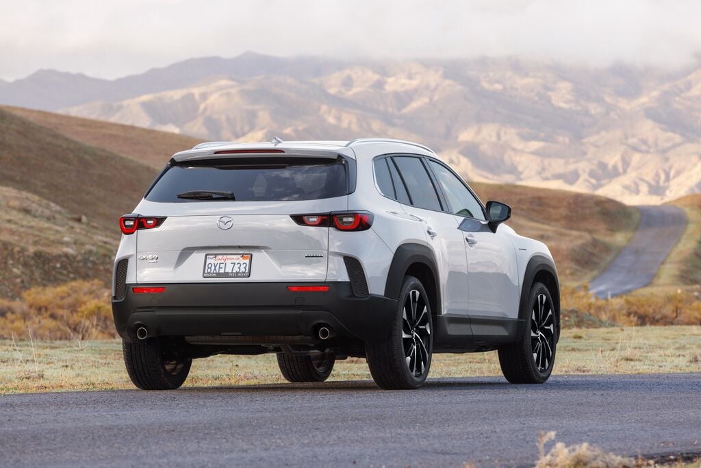 Vue arrière du Mazda CX-50 hybride 2025 avec la vue sur une route et des montagnes