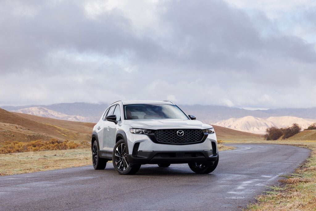 Mazda CX-50 hybride garé sur la route devant des montagnes.